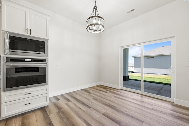 unfurnished dining area with baseboards, light wood-style flooring, visible vents, and a notable chandelier