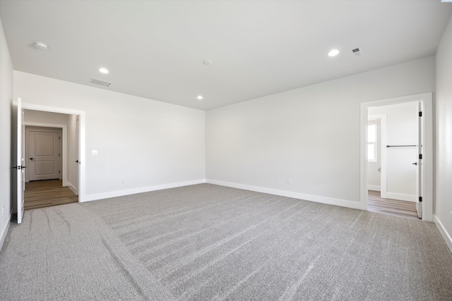 carpeted spare room featuring baseboards, visible vents, and recessed lighting