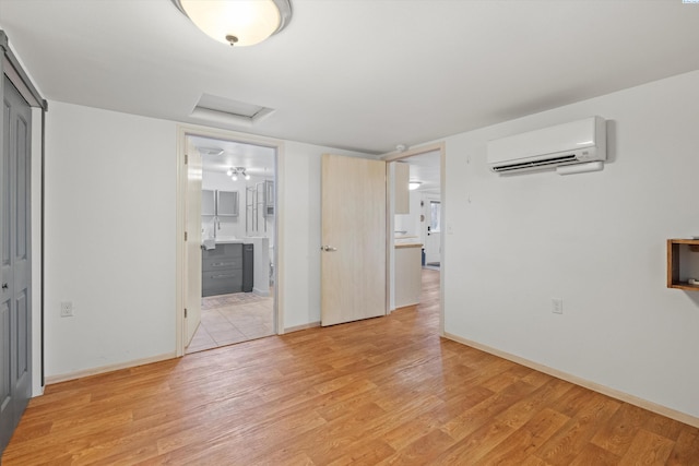 unfurnished room with a wall mounted air conditioner and light hardwood / wood-style floors