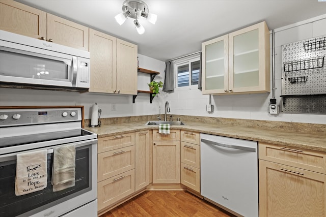 kitchen with sink, light brown cabinetry, white appliances, and light hardwood / wood-style floors