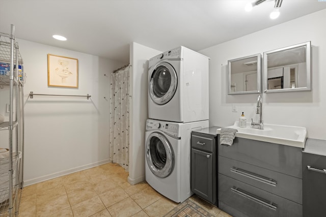 washroom featuring stacked washer and dryer, light tile patterned floors, and cabinets