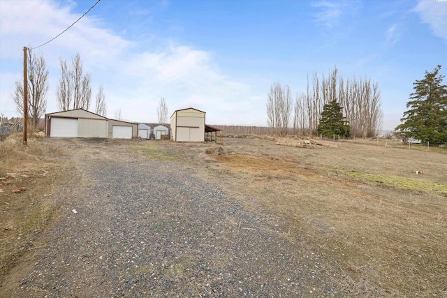 view of yard with a rural view, a garage, and an outdoor structure