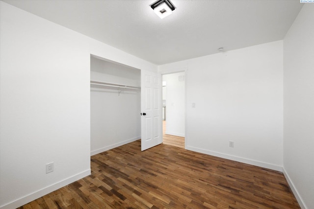 unfurnished bedroom with a closet, baseboards, and wood finished floors