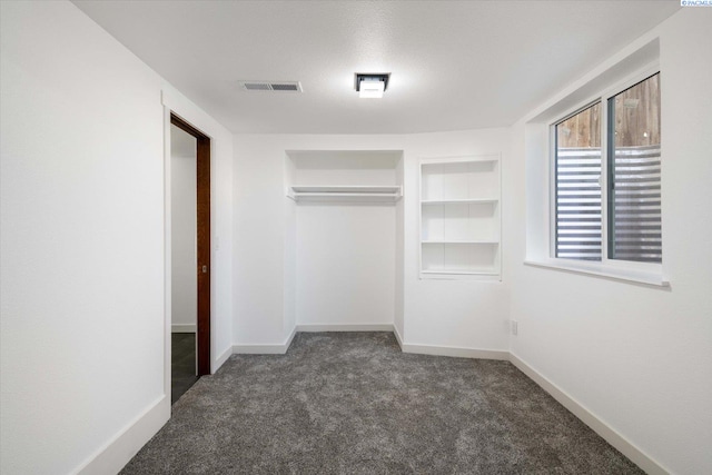 unfurnished bedroom featuring a closet, dark carpet, visible vents, and baseboards