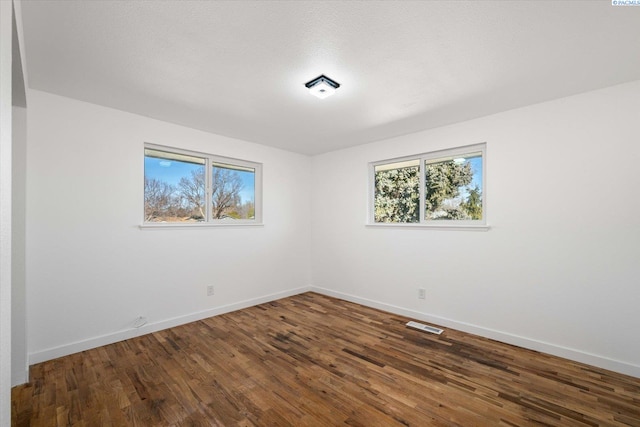 spare room featuring plenty of natural light, baseboards, and wood finished floors