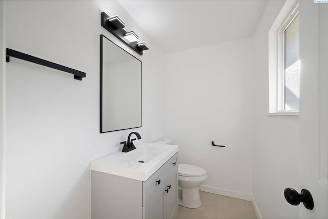 bathroom with toilet, baseboards, and vanity