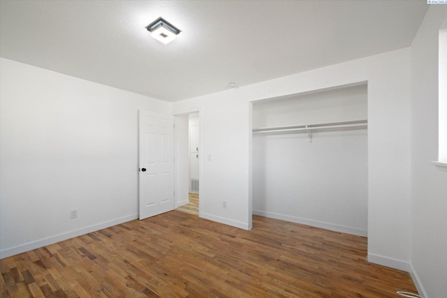 unfurnished bedroom featuring a closet, wood finished floors, and baseboards