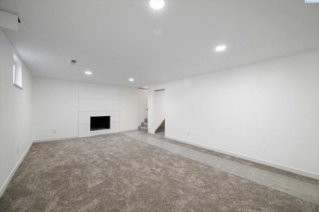 unfurnished living room with baseboards, visible vents, a tiled fireplace, carpet floors, and recessed lighting