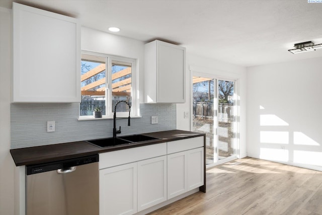 kitchen with backsplash, stainless steel dishwasher, white cabinetry, a sink, and light wood-type flooring