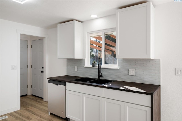 kitchen with a sink, white cabinetry, light wood-type flooring, dishwasher, and tasteful backsplash