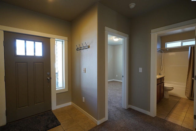 entrance foyer with baseboards, a healthy amount of sunlight, and light tile patterned flooring