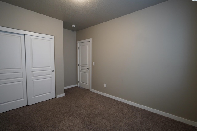 unfurnished bedroom featuring baseboards, carpet flooring, a textured ceiling, and a closet