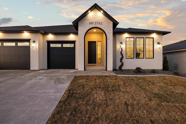 view of front of house with a garage, a yard, driveway, and stucco siding