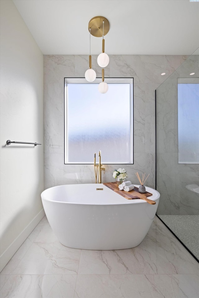 bathroom featuring stone wall, marble finish floor, a soaking tub, and a marble finish shower