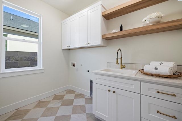 clothes washing area with cabinet space, hookup for a washing machine, hookup for an electric dryer, light floors, and a sink