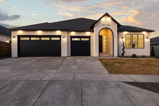 view of front of home with an attached garage, a shingled roof, concrete driveway, and stucco siding