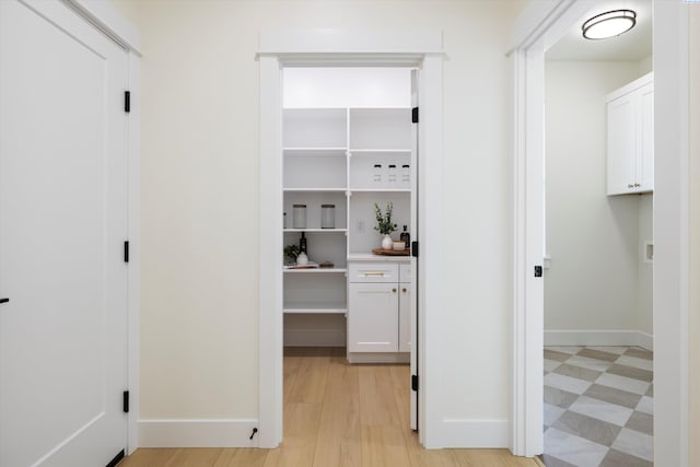 corridor featuring light wood-style floors and baseboards