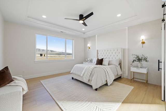 bedroom with light wood-type flooring, baseboards, a raised ceiling, and recessed lighting