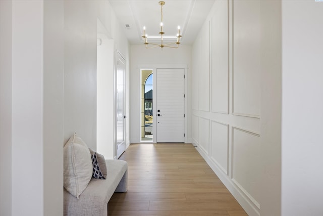 foyer entrance featuring light wood-type flooring and a chandelier