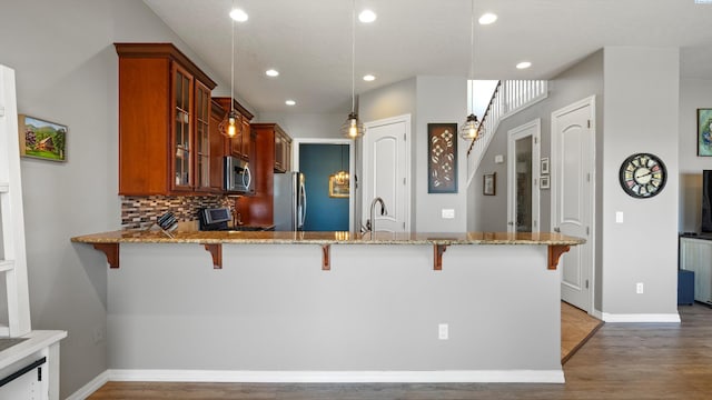 2876 Crosswater Loop, Richland, WA 99354 - kitchen with stainless steel appliances, a breakfast bar, glass insert cabinets, light stone counters, and wood finished floors