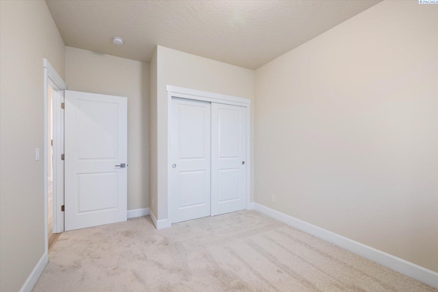 unfurnished bedroom featuring light carpet and a closet