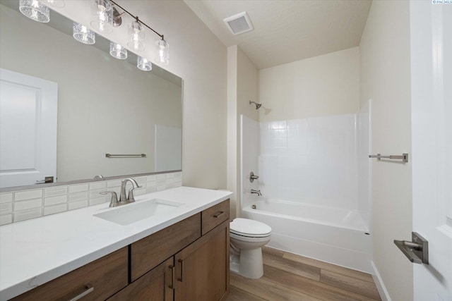 full bathroom with hardwood / wood-style floors, backsplash, vanity, shower / washtub combination, and toilet