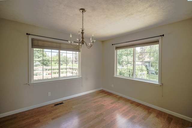 610 Dilke St, Pullman, WA 99163 - empty room with a chandelier, wood finished floors, and a textured ceiling