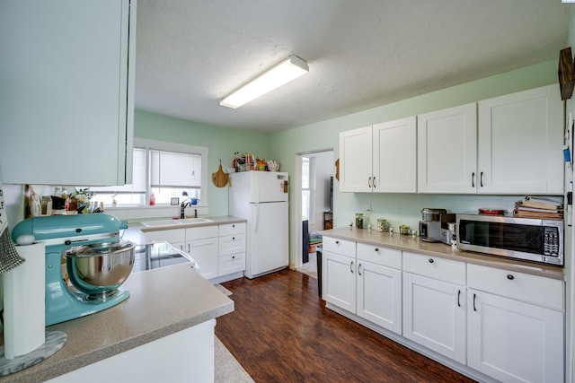 110 W Cannon St, Palouse, WA 99161 - kitchen with stainless steel microwave, freestanding refrigerator, a sink, and white cabinetry