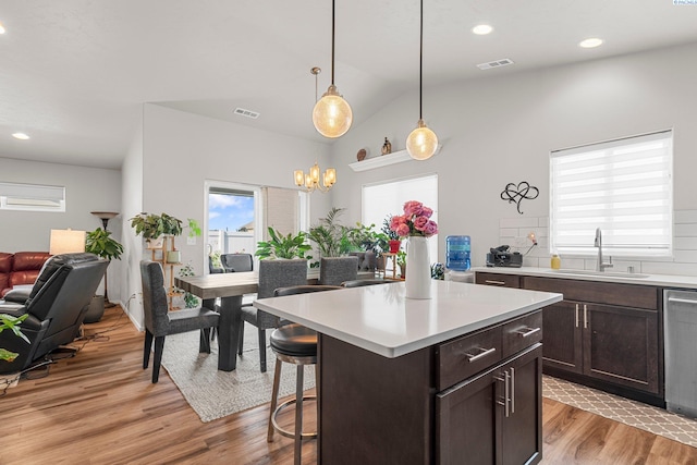 6217 Sidon Ln, Pasco, WA 99301 - kitchen with a sink, light wood-style flooring, dark brown cabinetry, a kitchen bar, and light countertops