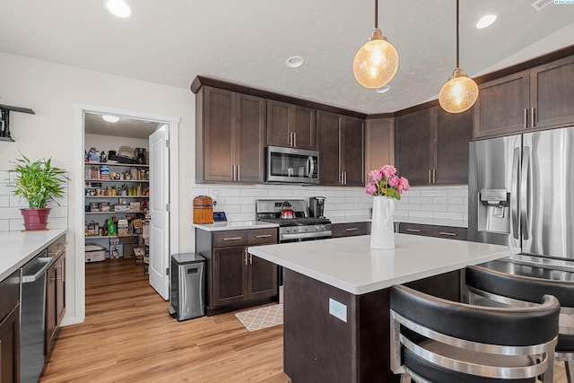 6217 Sidon Ln, Pasco, WA 99301 - kitchen with appliances with stainless steel finishes, dark brown cabinets, light countertops, light wood-type flooring, and tasteful backsplash