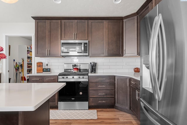 6217 Sidon Ln, Pasco, WA 99301 - kitchen featuring appliances with stainless steel finishes, light countertops, dark brown cabinetry, and backsplash