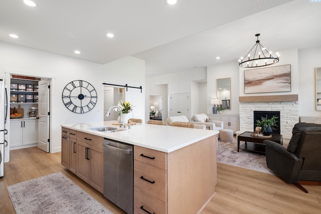 kitchen with a sink, stainless steel appliances, light wood-style flooring, light countertops, and open floor plan