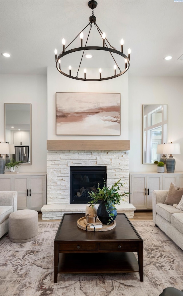 living area featuring light wood-type flooring, recessed lighting, an inviting chandelier, and a fireplace