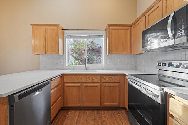 kitchen featuring appliances with stainless steel finishes, dark hardwood / wood-style floors, sink, decorative backsplash, and kitchen peninsula