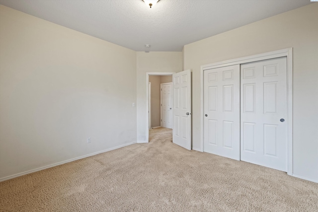 unfurnished bedroom featuring light colored carpet, a closet, and a textured ceiling