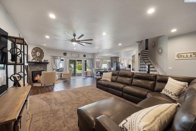 living area featuring hardwood / wood-style floors, recessed lighting, a stone fireplace, a ceiling fan, and stairway
