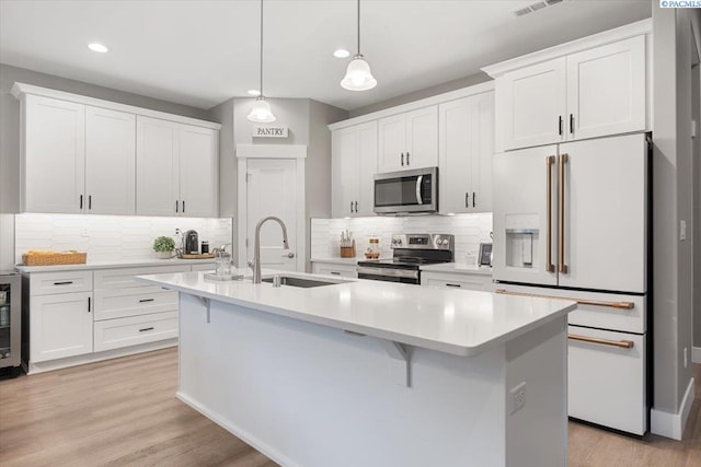 kitchen featuring decorative light fixtures, white cabinets, and appliances with stainless steel finishes