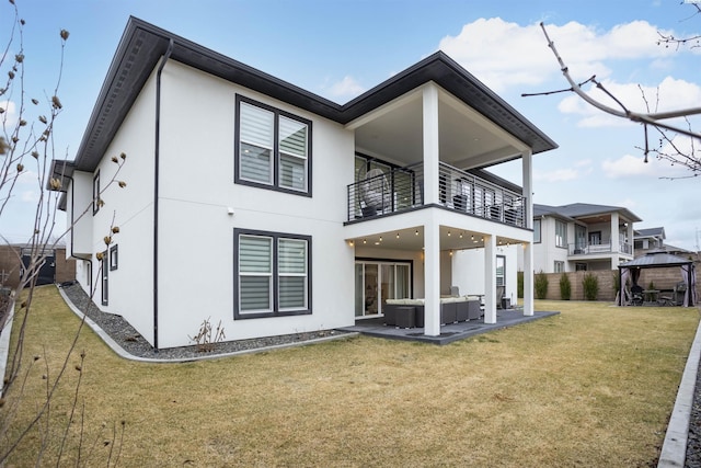 back of property featuring a yard, a gazebo, a patio, an outdoor living space, and a balcony