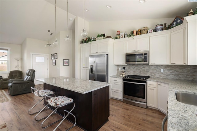 3763 S Sherman St, Kennewick, WA 99338 - kitchen with appliances with stainless steel finishes, wood finished floors, a kitchen bar, decorative backsplash, and high vaulted ceiling