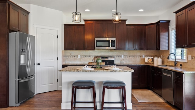 76704 E Timothy Ln, Kennewick, WA 99338 - kitchen with appliances with stainless steel finishes, a sink, a kitchen island, dark wood-style floors, and backsplash