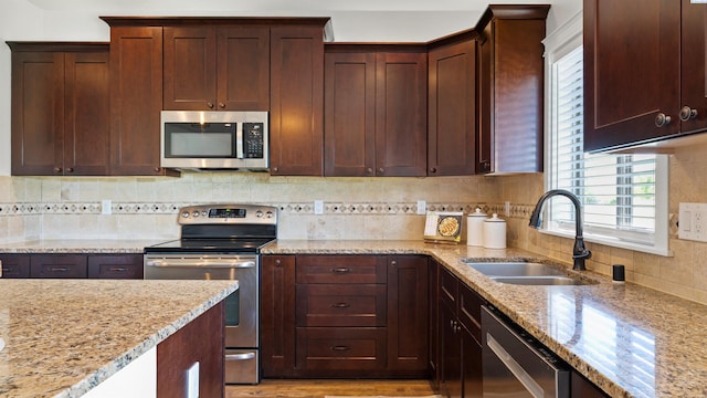 76704 E Timothy Ln, Kennewick, WA 99338 - kitchen with stainless steel appliances, a sink, light stone countertops, decorative backsplash, and dark brown cabinetry