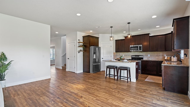 76704 E Timothy Ln, Kennewick, WA 99338 - kitchen with stainless steel appliances, a sink, a center island, dark brown cabinets, and backsplash
