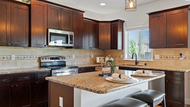 76704 E Timothy Ln, Kennewick, WA 99338 - kitchen with stainless steel appliances, a sink, a kitchen breakfast bar, light stone countertops, and a kitchen island