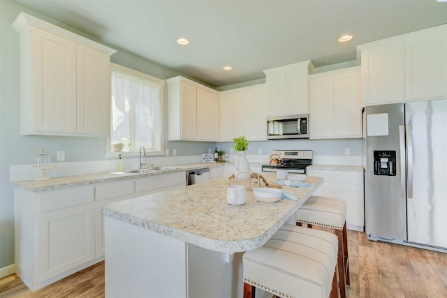 3915 Charleston Ln, Pasco, WA 99301 - kitchen featuring appliances with stainless steel finishes, a kitchen island, light wood-style floors, light countertops, and a breakfast bar area