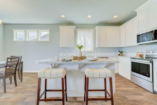3915 Charleston Ln, Pasco, WA 99301 - kitchen featuring electric stove, a kitchen breakfast bar, a kitchen island, plenty of natural light, and recessed lighting