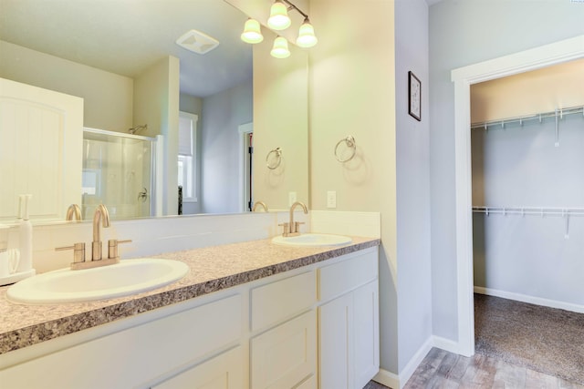 3915 Charleston Ln, Pasco, WA 99301 - bathroom with a stall shower, double vanity, a walk in closet, and wood finished floors