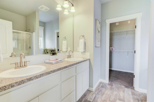 3915 Charleston Ln, Pasco, WA 99301 - bathroom featuring a stall shower, double vanity, wood finished floors, and a walk in closet