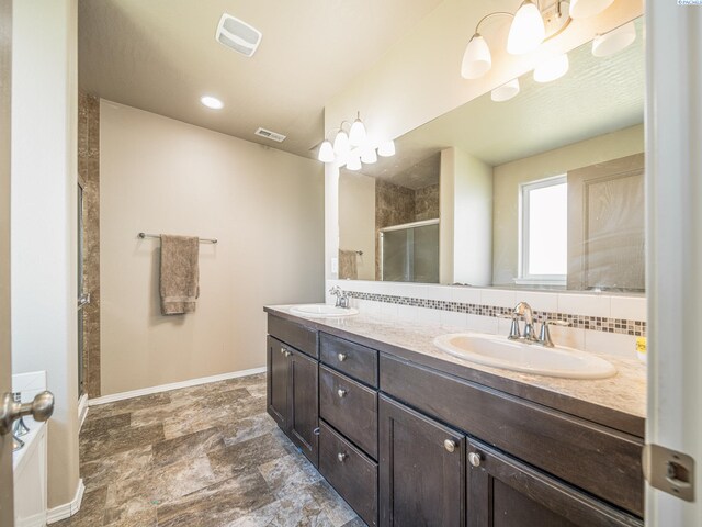 4268 Hedman Ct, Moses Lake, WA 98837 - bathroom with double vanity, a shower stall, stone finish floors, and backsplash