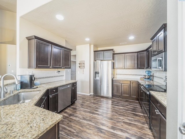 4268 Hedman Ct, Moses Lake, WA 98837 - kitchen with appliances with stainless steel finishes, light stone counters, backsplash, dark wood-type flooring, and a textured ceiling