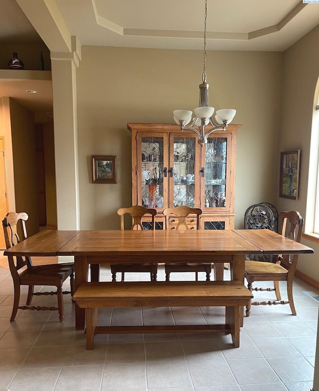 dining space with baseboards, light tile patterned flooring, a raised ceiling, and an inviting chandelier